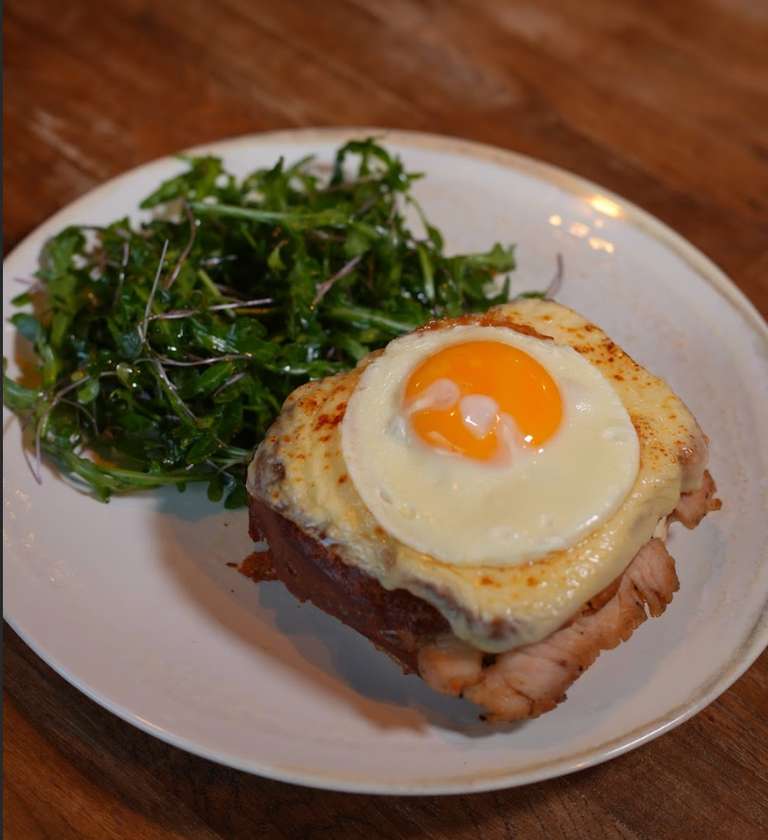 Croque Madame with Ham, Fried Egg, and Fresh Lettuce Leaves