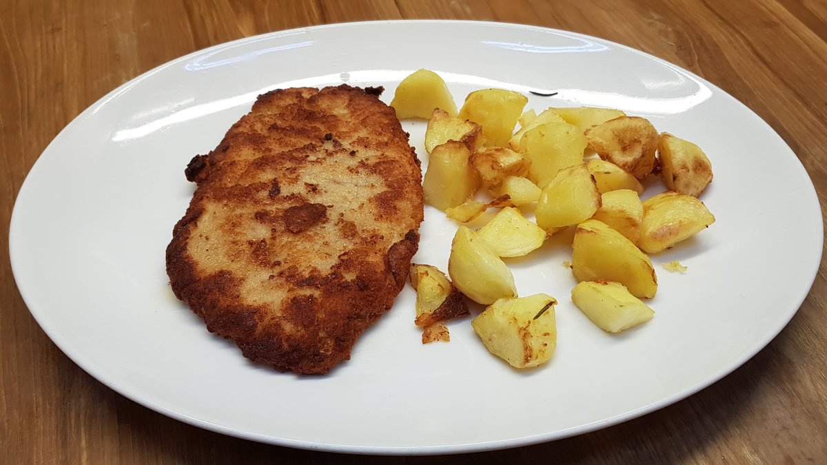 Cotoletta alla milanese croccante di maiale servita con patate arrosto